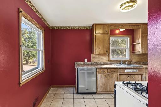Sunlit kitchen with wood cabinetry, spacious counters, gas range, and windows overlooking the yard.