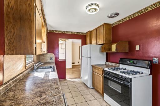 Functional galley kitchen with wood cabinetry, ample counter space, tile flooring, and adjacent dining access.