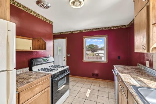 Kitchen view highlighting wood cabinetry, multiple windows, tile flooring, and a practical work triangle.