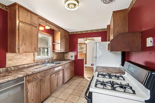 Kitchen workspace featuring extensive wood cabinetry, a window above the sink, tile flooring, and natural light.