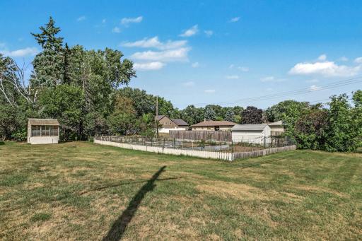Expansive backyard with open lawn, mature trees, raised garden beds, and space for outdoor recreation.
