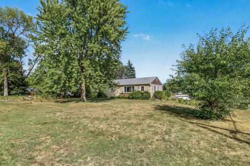 Large yard offering mature shade trees, open lawn, garden areas, and a peaceful residential setting.