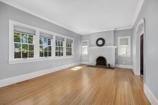 Spacious and filled with natural light, this inviting living room features large windows and a cozy fireplace.