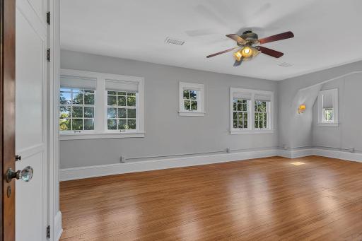 The upper level features two spacious bedrooms and a large full bathroom. This is the larger of the two upstairs bedrooms, offering an abundance of windows that fill the space with natural light.
