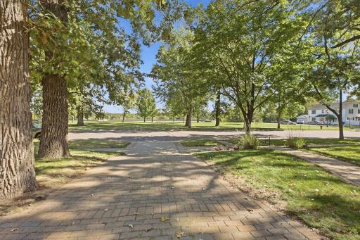 Beautiful view down the paver stone driveway toward the park directly across the street, highlighting this homeâs desirable setting.