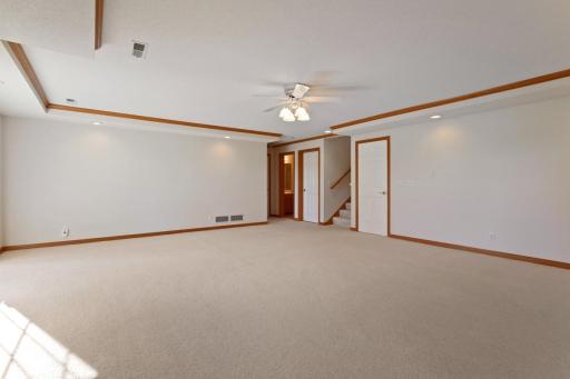 Lower level family room with ceiling fan and crown mouldings