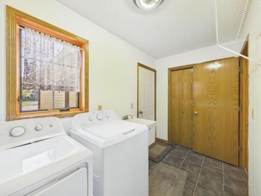 Main-level laundry off the garage includes a utility sink, storage, and closet space.