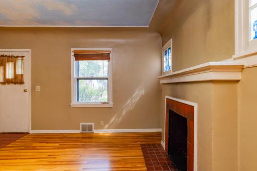 Main floor living room features hardwood flooring and wood burning fireplace.