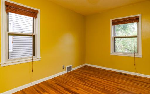 Main floor bedroom with two windows and hardwood flooring.