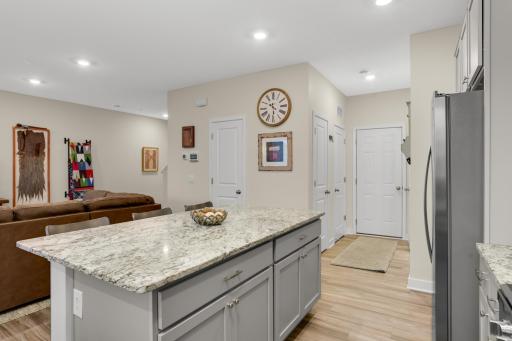Spacious kitchen featuring a large center island, granite countertops, abundant counter space, and stainless-steel appliances. A bright kitchen window overlooks the covered patio, creating a welcoming connection to the outdoor living space.