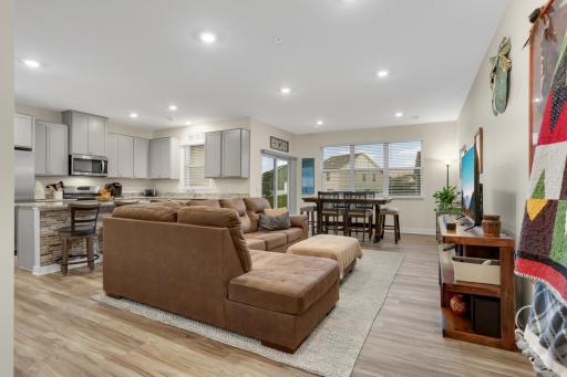 Spacious open-concept main floor featuring inviting living, dining & kitchen areas with luxury LVP flooring, granite countertops, stainless-steel appliances, and a gas range—perfect for everyday living and entertaining.