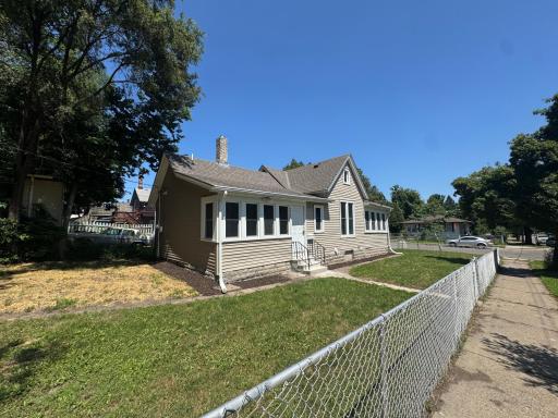 Charming bungalow with fenced front yard, gabled roofline, and classic sunroom windows.jpg
