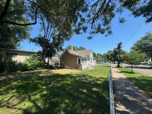 Fenced backyard with mature shade trees and a sidewalk path