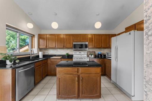 Well-appointed kitchen features granite countertops and a travertine-style tile backsplash.