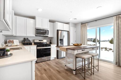 Modern kitchen with white cabinets, quartz countertops and stainless appliances. Model photos. Options and colors will vary.
