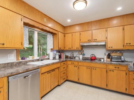 Generous kitchen workspace with abundant cabinetry, counter space, and a new dishwasher.