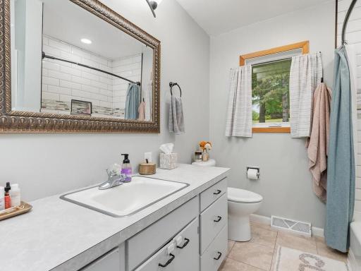 Updated main-level bathroom with a spacious vanity and tiled tub surround.