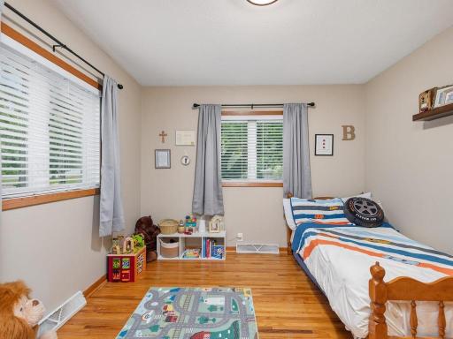Main-level bedroom with hardwood floors and windows on two sides.