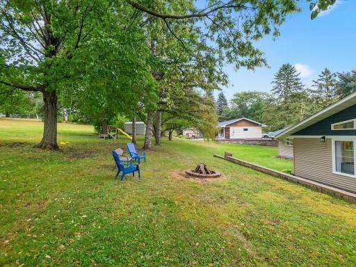 Spacious backyard with mature shade trees and a fire pit area.