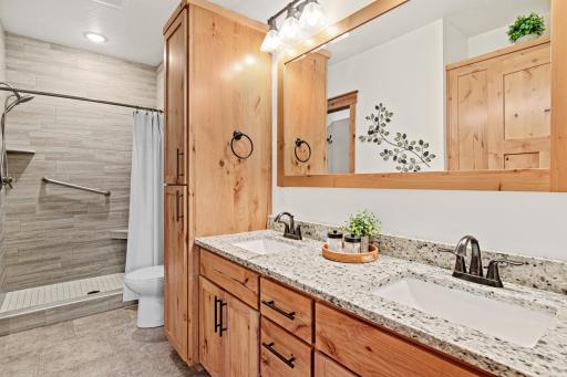 The private primary bath features a double vanity, granite counters, ample storage, and a tiled walk-in shower.