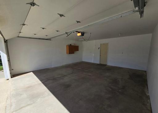 Few extra storage cabinets, attic access in ceiling, & door into the house. Garage door opener with 2 remotes.