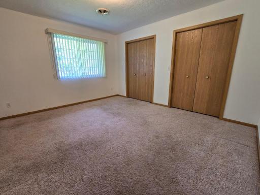 Primary NE bedroom. Features carpeting and double closets