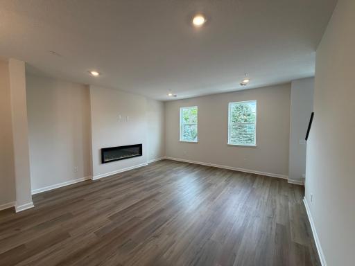 This spacious living room has excellent scenery featuring large windows, a fireplace, and enough space for even the biggest couches.
