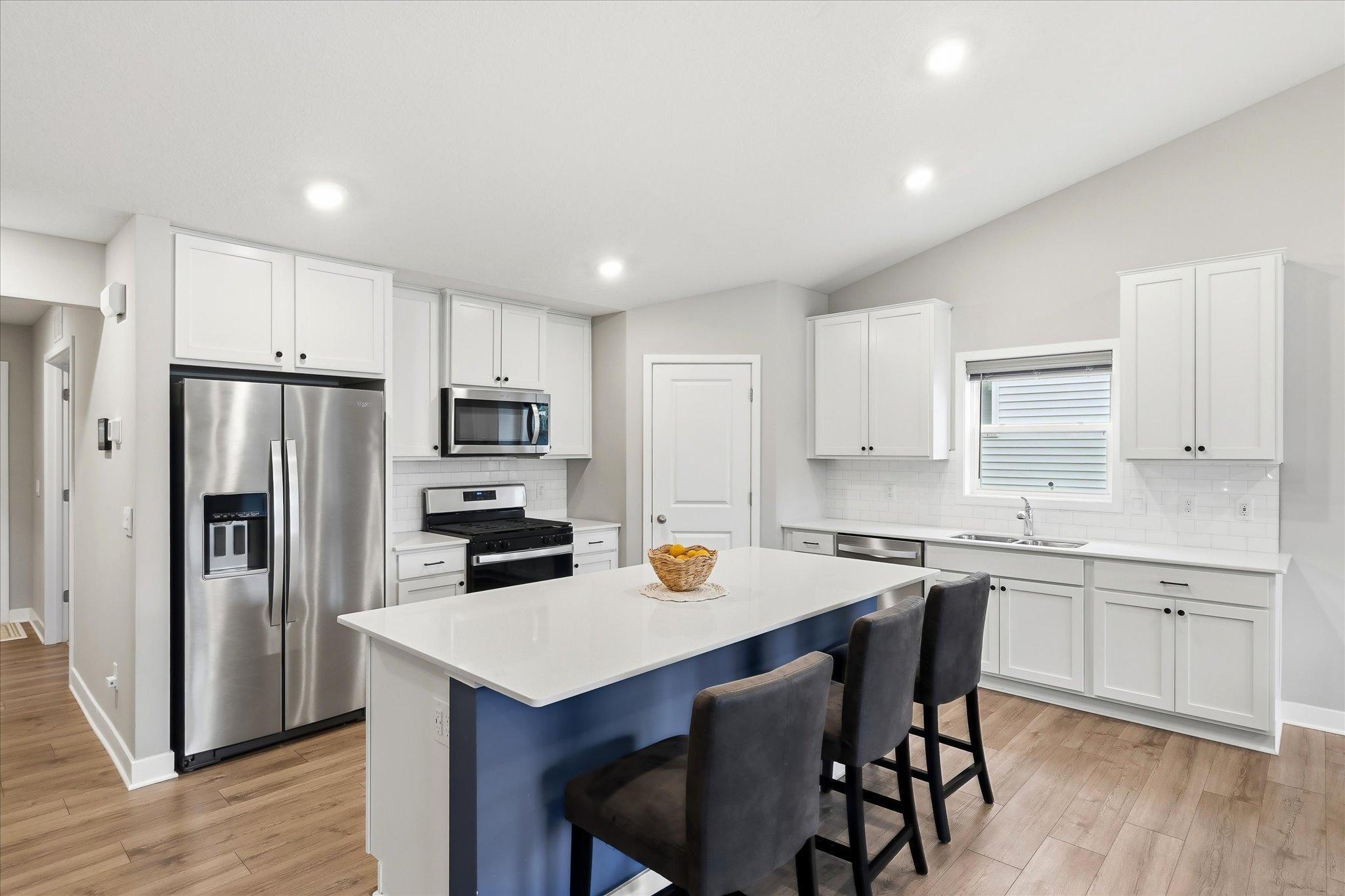 The heart of the home! An open kitchen with a center island, stainless steel appliances, and beautiful tiled backsplash.
