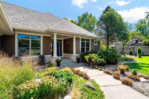 The front of house has a paver patio sitting area that overlooks a manicured entry, with well designed perennials.