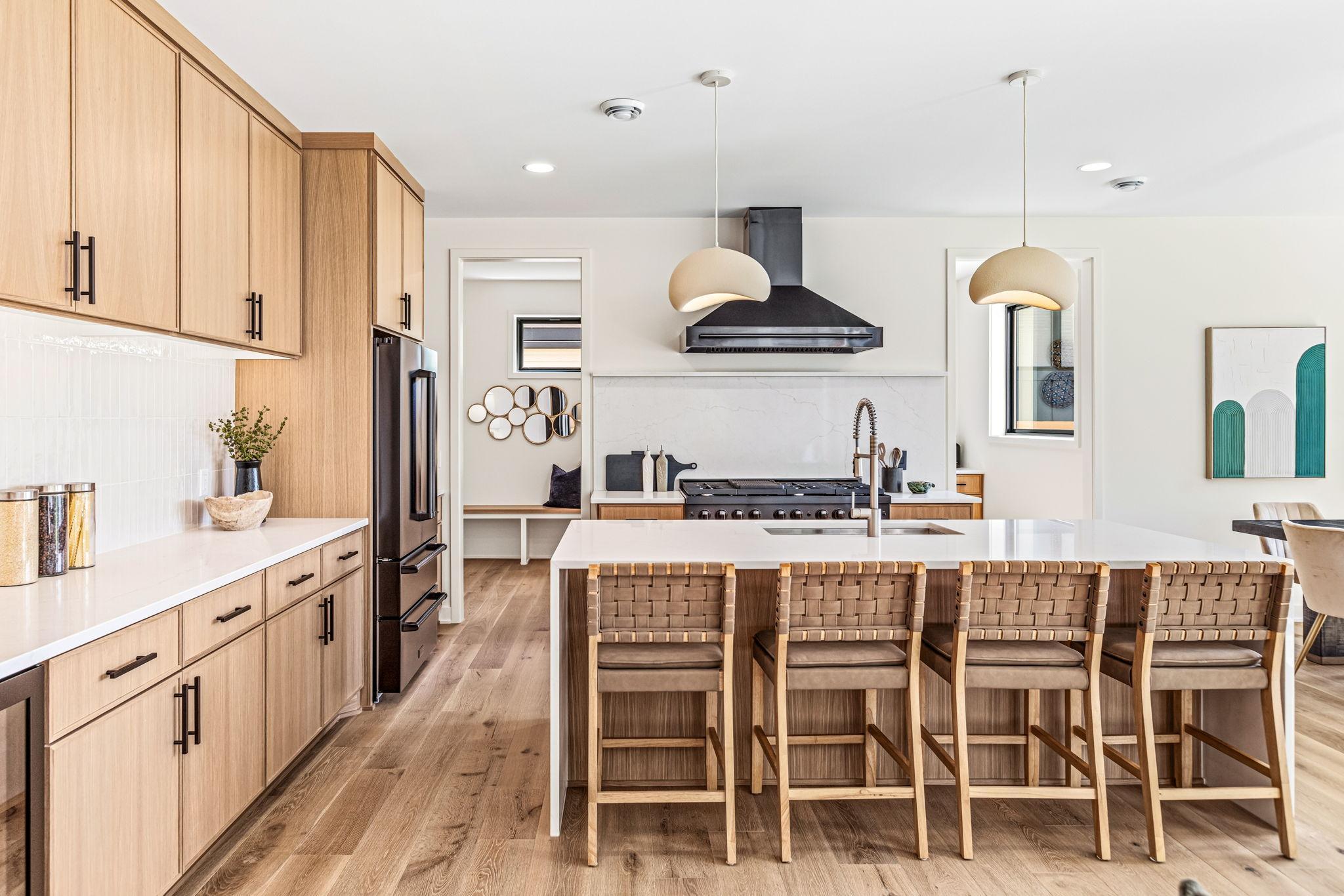 Chef's kitchen with black ZLINE appliances, white oak cabinetry with soft close doors and drawers, tons of counterspace, and a waterfall quartz island.