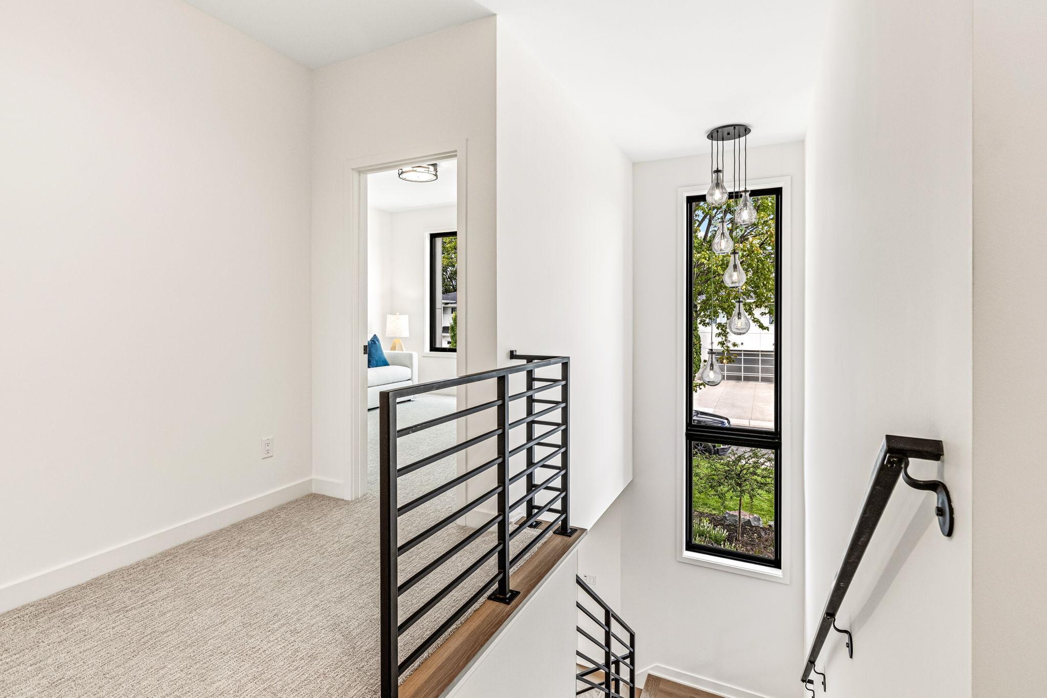Gorgeous black modern rail paired with a statement window spanning the staircase up.