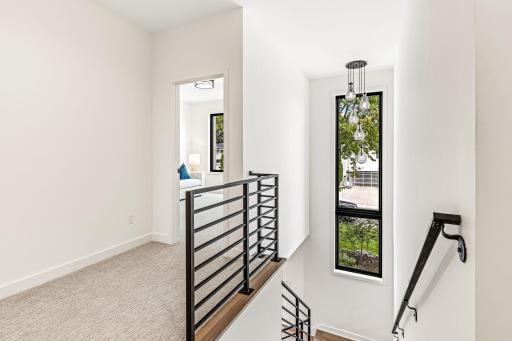 Gorgeous black modern rail paired with a statement window spanning the staircase up.