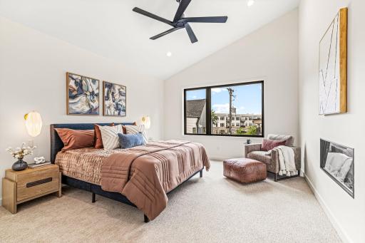 Luxurious vaulted owners suite with sitting space and linear fireplace.
