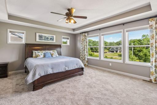 Primary bedroom with tray vault ceiling and picture windows.