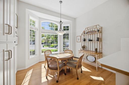 Bayed informal dining are with round top window and wood floors.
