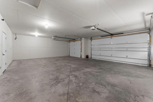 Expansive finished three-car attached garage offering exceptional functionality, with convenient access to both the backyard and interior of the home.