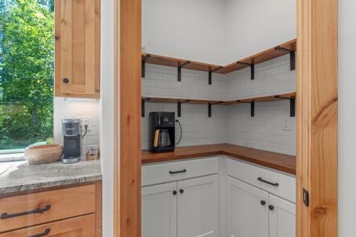 Pantry built-ins with open shelving and a stylish tile backsplash.