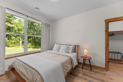 Second bedroom on the main level with a spacious walk-in closet and wooded front yard views.