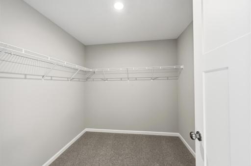 The primary walk-in closet provides plenty of dedicated space to keep clothing, shoes, and everyday essentials organized. *photos of previously staged home, same floor plan and finishes however some features are not exact*