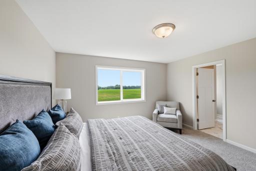 A spacious primary bedroom offers plenty of room to create a comfortable place to begin and end each day. *photos of previously staged home, same floor plan and finishes however some features are not exact*