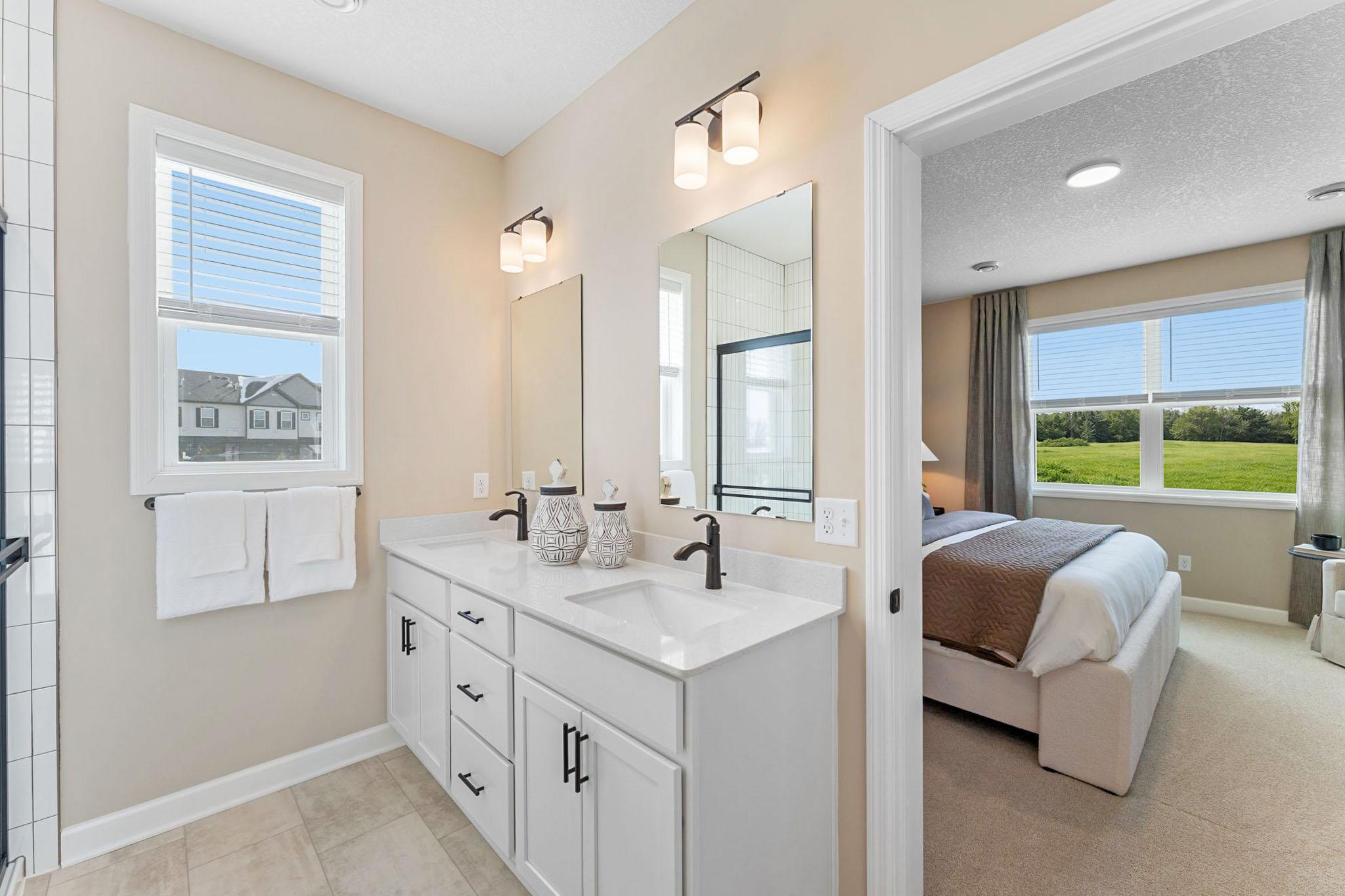 The quartz-topped vanity showcases rectangular dual sinks, stylish cabinetry and individual glass mirrors