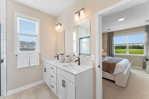 The quartz-topped vanity showcases rectangular dual sinks, stylish cabinetry and individual glass mirrors