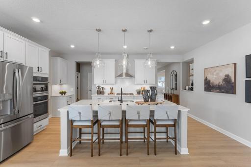 At the focal point of this modern kitchen is an inviting center island that doubles as a breakfast bar, surrounded by gleaming quartz countertops and a high-end wall oven to craft delicious meals of all sizes.