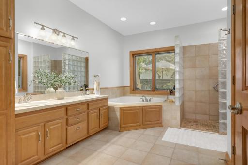 Ensuite retreat with heated tile floor, dual sinks, whirlpool tub, walk-in shower and private toilet closet
