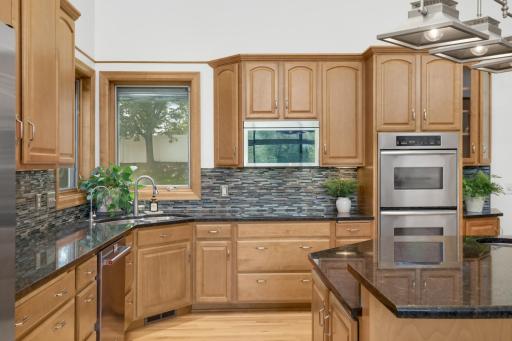 Gourmet kitchen with dual ovens, stainless steel appliances, stove top range, and an abundance of cabinetry