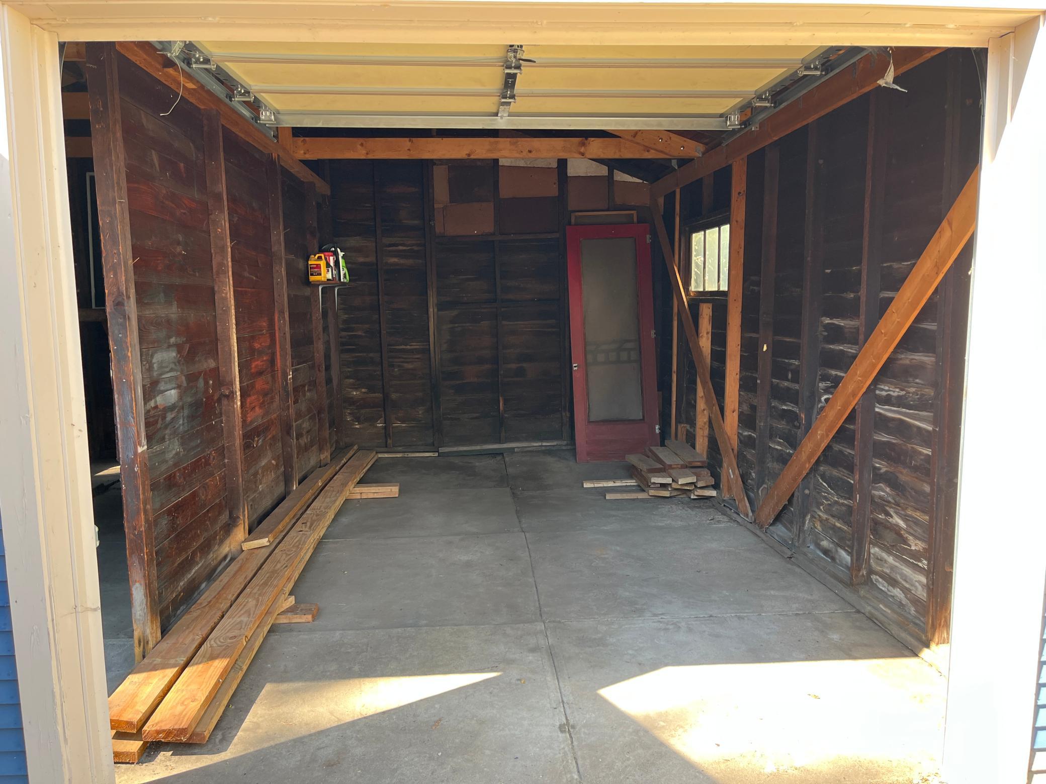 Double garage. This is the side with the roll up door. The opening is 7' 9" wide x 6' 10" tall. Leftover decking materials visible.