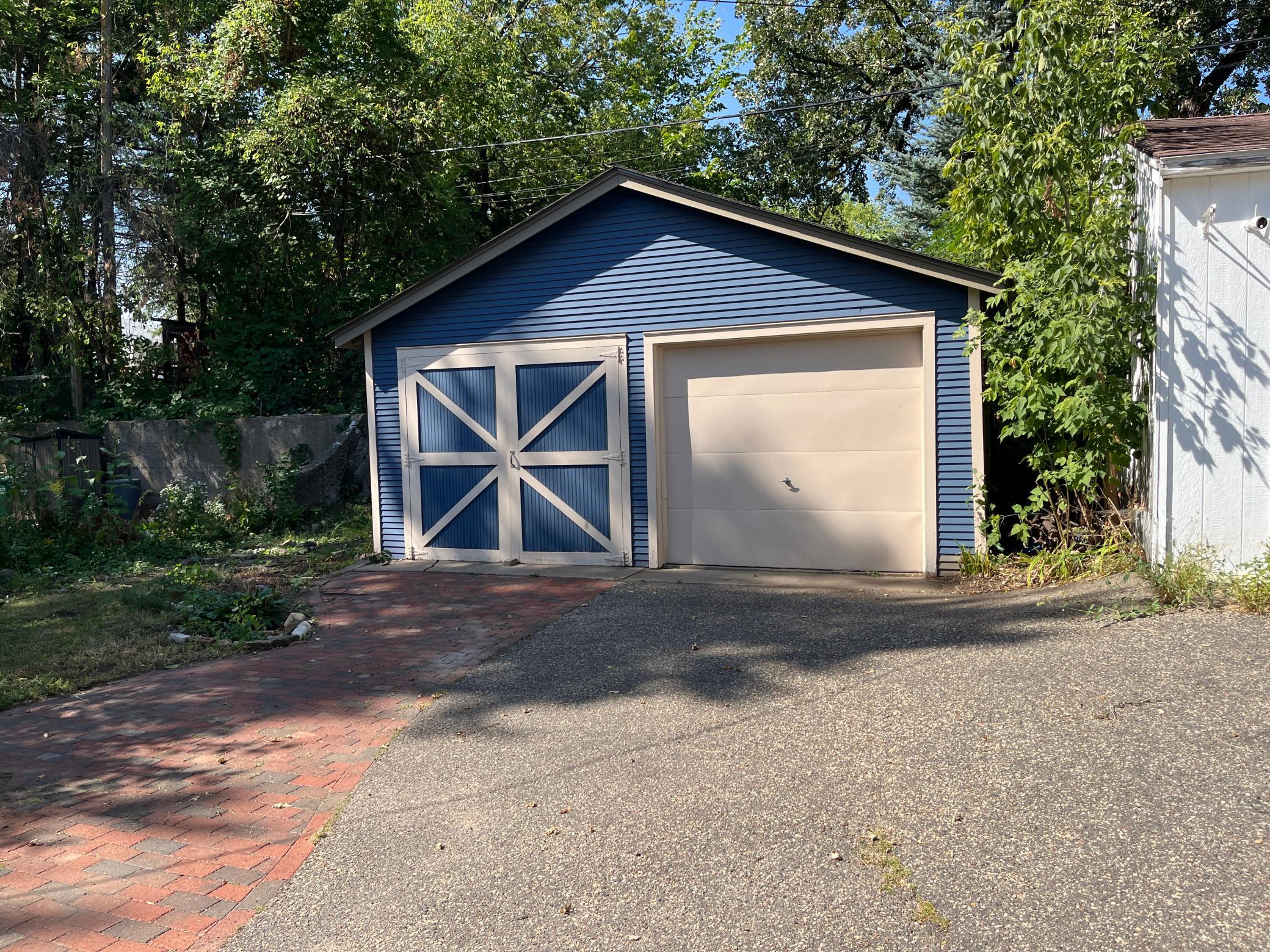 Double garage. "Barn doors" and a roll up door. 18 feet deep, 19 feet wide. Asphalt and brick pavement.