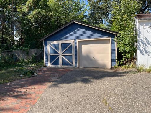 Double garage. "Barn doors" and a roll up door. 18 feet deep, 19 feet wide. Asphalt and brick pavement.
