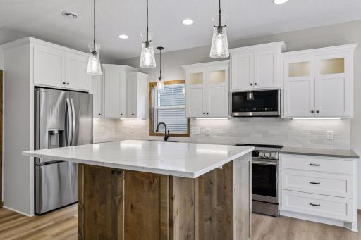 This opens to a contrasting white kitchen with a heightened center island, tile backsplash and Quartz countertops.