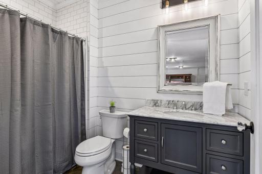 The lower-level 3/4 bath showcases charming shiplap accents, stylish finishes, and thoughtful details that perfectly complement the home's coastal-inspired design and relaxed lakeside feel.